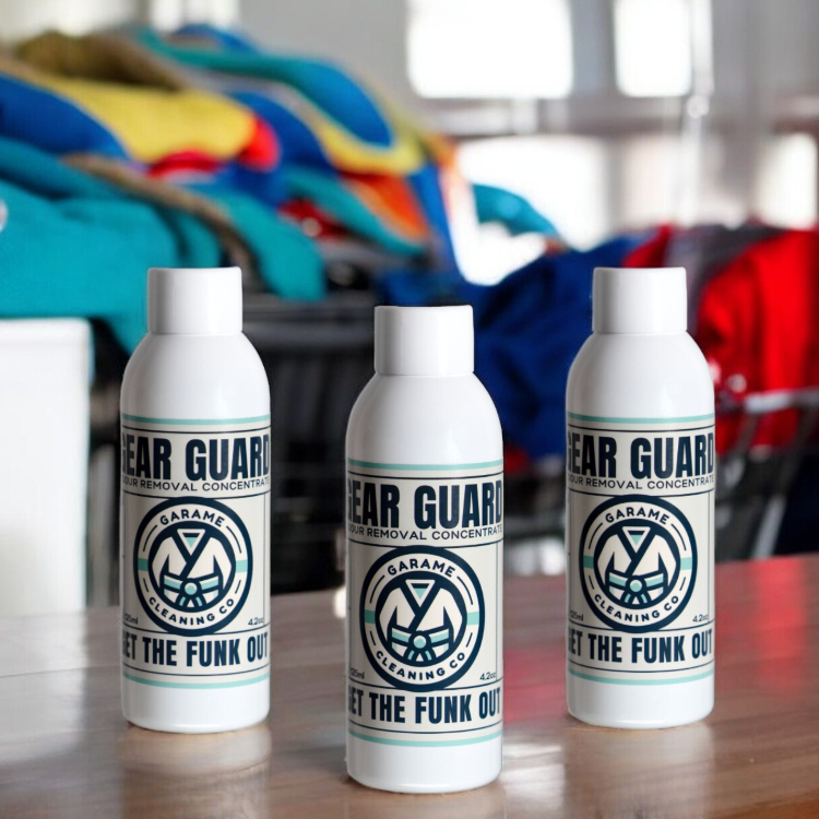 Three bottles of Gear Guard odour removal concentrate displayed side by side on a timber surface, showcasing the mid-sized bundle option. The bottles are uniformly branded with a white bottle. The label has a sky blue border with dark blue writing. The Garame Cleaning Co logo is in the centre, Gear Guard written above and Get the funk out below.