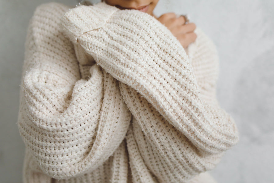 A close-up portrait of a person in a white knitted sweater with long sleeves, offering a warm and cozy feel.
Photo by Polina Tankilevitch on Pexels. 